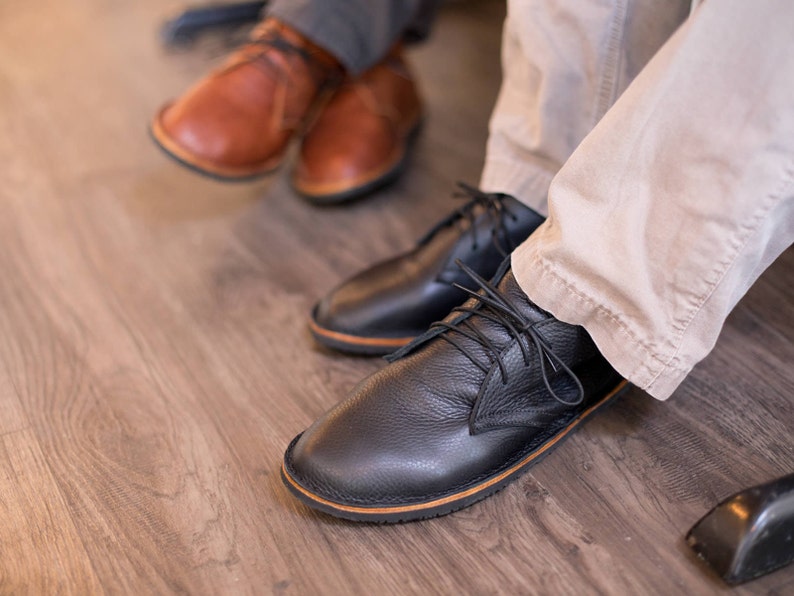 Puede incluir: Dos pares de zapatos de cuero. Un par es marr&oacute;n y el otro par es negro. Los zapatos negros tienen cordones.