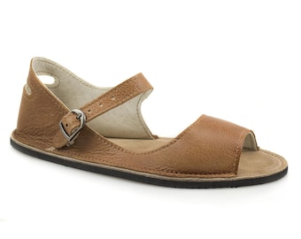 Puede incluir: Sandalias de cuero marrón claro con cierre de hebilla y puntera abierta. Las sandalias tienen una suela plana y un diseño cómodo.