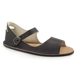 May include: Black leather sandals with a buckle closure and an open toe. The sandals have a flat sole and a comfortable design.