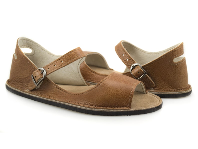 Puede incluir: Un par de sandalias de cuero marr&oacute;n con cierre de hebilla y puntera abierta. Las sandalias tienen un dise&ntilde;o sencillo y est&aacute;n hechas de un cuero suave y c&oacute;modo.