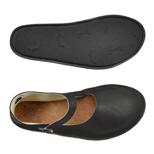 May include: Black leather ballet flats with a strap across the foot and a buckle closure. The shoes have a brown leather insole and a black rubber outsole.