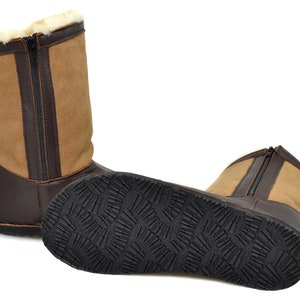May include: A pair of brown leather boots with a zipper up the back. The boots have a tan suede upper and a black rubber sole.