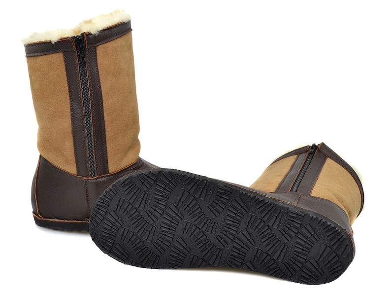 May include: A pair of brown leather boots with a zipper up the back. The boots have a tan suede upper and a black rubber sole.