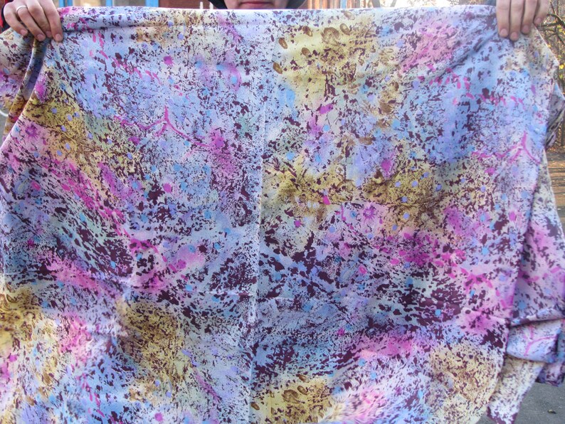 May include: A colorful fabric with a tie-dye pattern in shades of blue, pink, purple, and brown. The fabric has a mottled, textured appearance.