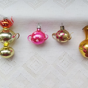 Könnte beinhalten: Fünf antike gläserne Weihnachtsbaumschmuckstücke in Form von Teekannen und einer Vase. Die Ornamente sind mit goldener, rosa und roter Farbe verziert.