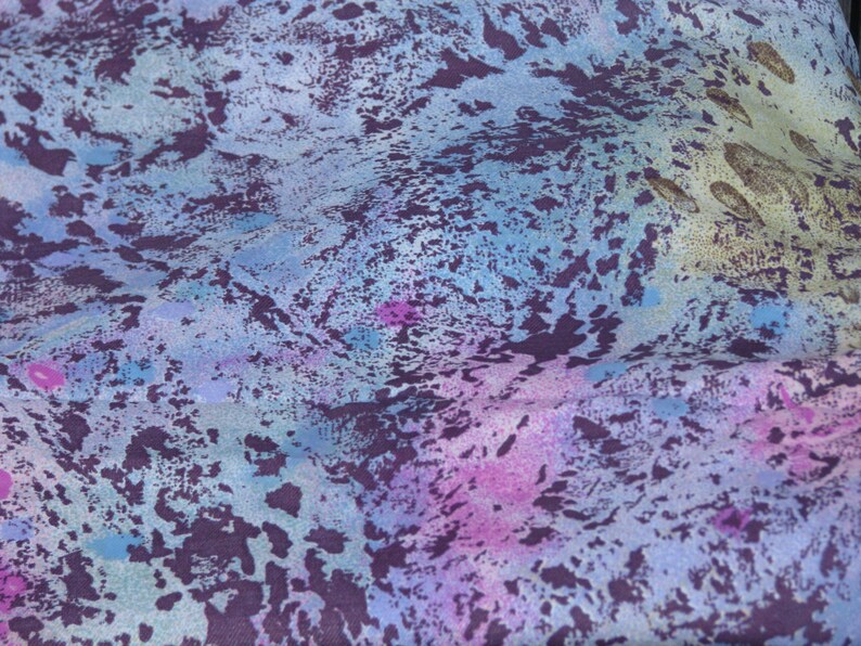 May include: Abstract fabric with a blue, purple, and pink color scheme. The fabric has a mottled, textured appearance with a subtle pattern.