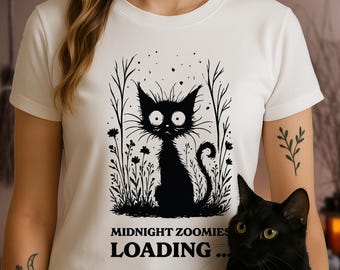 May include: White t-shirt with a black and white illustration of a cat with the text "Midnight Zoomies Loading..."