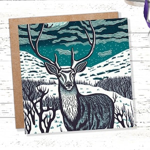 Carte cerf linogravure noir et bleu enneigé paysage d'hiver Highlands scène de neige montagnes ciel salutations pour la famille amis Noël 2025 Merci