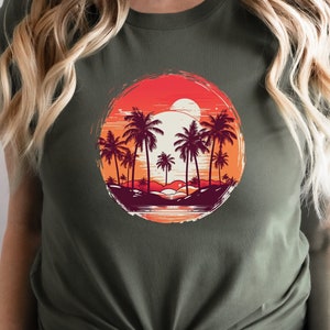 May include: A green t-shirt with a circular graphic of palm trees and a sunset. The graphic is in shades of red, orange, yellow, and brown.