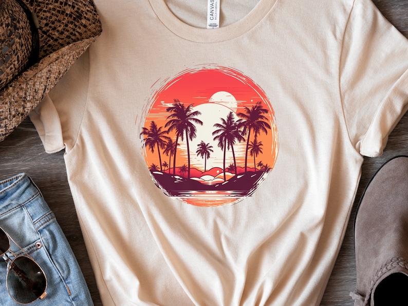 May include: A beige t-shirt with a graphic print of a sunset over a beach with palm trees. The graphic is in a circle with a distressed look.