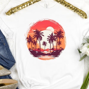 May include: White t-shirt with a graphic of palm trees and a sunset in a circle. The graphic is in shades of red, orange, and yellow.