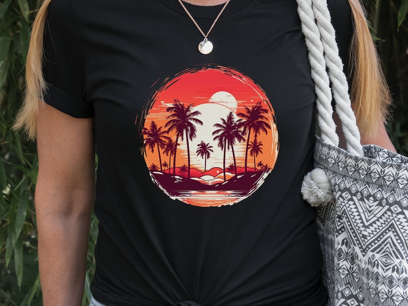May include: Black t-shirt with a graphic of palm trees and a sunset in a circle. The graphic is in shades of orange, red, and yellow.