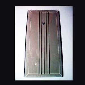 May include: A rectangular, light gray, metal plate with four vertical grooves and a small, round, black screw in the center.