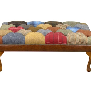 May include: A patchwork footstool with a brown leather base and wooden legs. The top is covered in a variety of colorful tweed fabrics.
