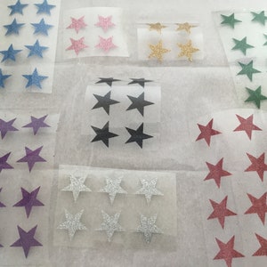 May include: An assortment of star-shaped stickers in a range of colours, such as blue, pink, gold, green, purple, silver, black, and red. The stickers have a glittery finish and are on clear backing paper. Suitable for crafts and decorations.
