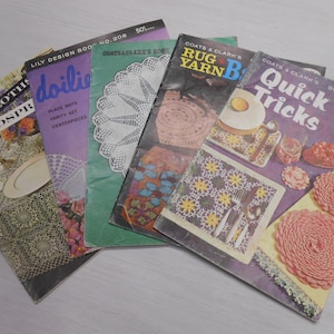 May include: Five vintage crochet pattern books with colorful covers. The books feature titles like "Tablecloths & Bedspreads", "Doilies", "Coats & Clark's Rug Yarn Book", and "Coats & Clark's Quick Tricks".