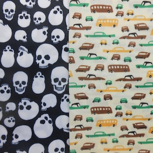 May include: A black fabric with a white skull pattern on one side and a white fabric with a brown and green car pattern on the other side.