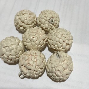 Op de afbeelding: Zes witte keramische ornamenten met een getextureerd oppervlak. Elk ornament heeft een klein gaatje bovenaan om op te hangen.