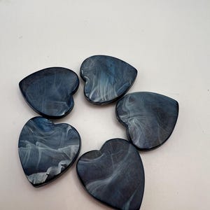 May include: Five heart-shaped decorative pieces. Each piece is a deep blue with swirling white patterns, creating a marbled effect. The hearts are arranged in a circular pattern against a white background.
