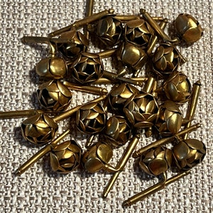 May include: A collection of vintage gold-toned cufflinks. Each cufflink features a spherical design with petal-like details and a T-bar closure. The cufflinks are scattered on a textured surface.