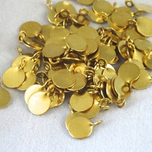 May include: A pile of gold-colored metal discs with a small loop on each one. The discs are about 1 inch in diameter.