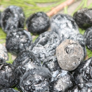 May include: A collection of black and white tumbled stones with a variety of patterns and textures. The stones are smooth and polished, and they have a natural, organic look.