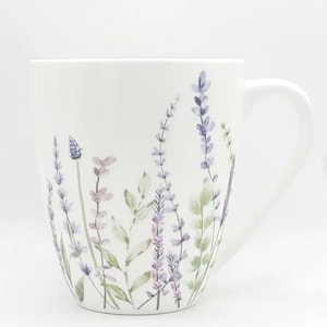 May include: White ceramic mug with a curved handle, decorated with watercolor illustrations of lavender sprigs in shades of purple, green, and pink. The floral design is set against a plain white background.