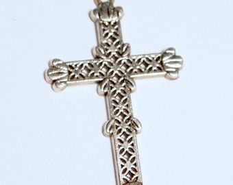 May include: A silver filigree cross pendant with a detailed design. The cross is ornate and has a delicate, intricate pattern.
