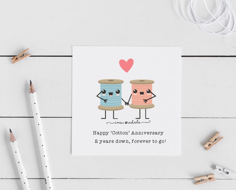 May include: A greeting card with a pink heart and two cartoon spools of thread, one blue and one pink, holding hands. The text reads "Happy 'Cotton' Anniversary 2 years down, forever to go!"