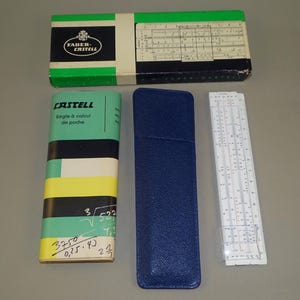 Peut inclure: Ensemble de règles à calcul et étuis Faber-Castell vintage. L'ensemble comprend une longue boîte verte et blanche, un étui cylindrique avec une règle à calcul, un étui en cuir bleu et une règle à calcul.