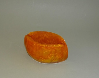 Peut inclure: Un petit cendrier en céramique marbré orange et jaune.