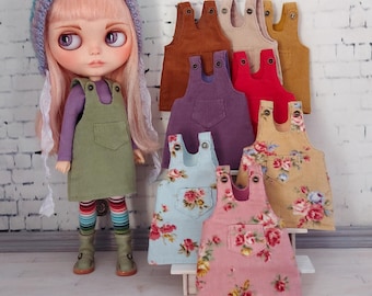 May include: A collection of eight pinafore dresses for Blythe dolls. The dresses are made of different fabrics, including corduroy, denim, and floral print. The dresses are in various colors, including brown, beige, red, purple, blue, and pink.