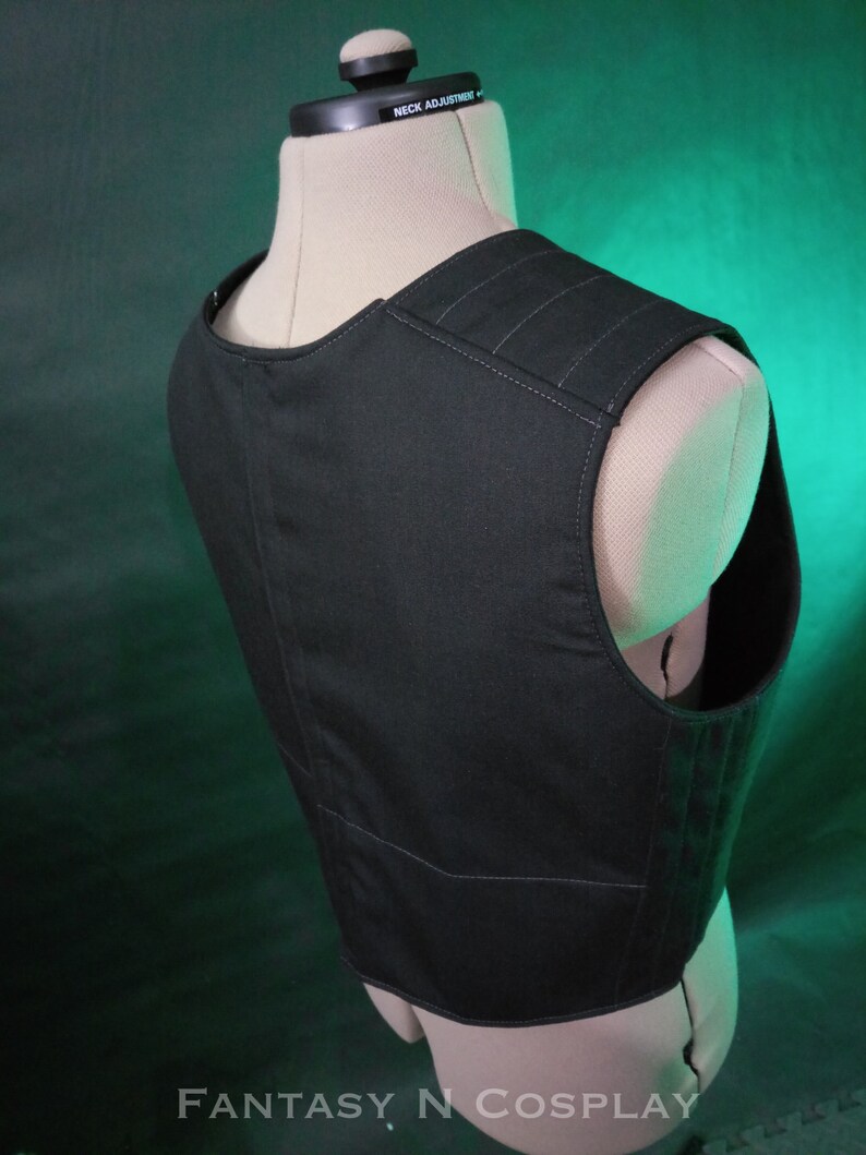 May include: Black sleeveless vest with a zipper closure and multiple pockets. The vest has a textured fabric and is made of a durable material.