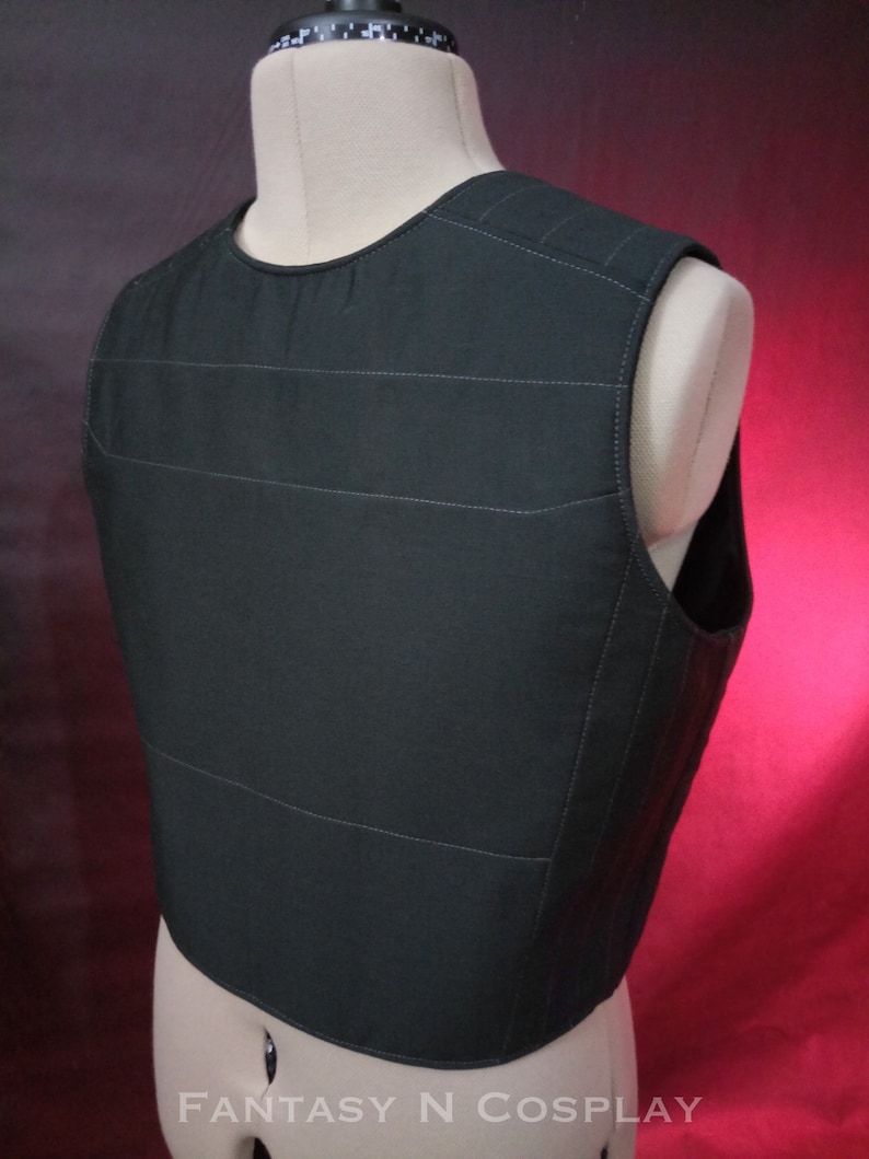 May include: Black quilted vest with a straight neckline and sleeveless design. The vest has a subtle sheen and is made of a lightweight fabric.