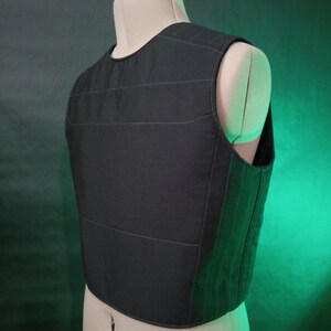 May include: Black quilted vest with a straight neckline and sleeveless design. The vest has a fitted silhouette and is made of a soft, comfortable fabric.