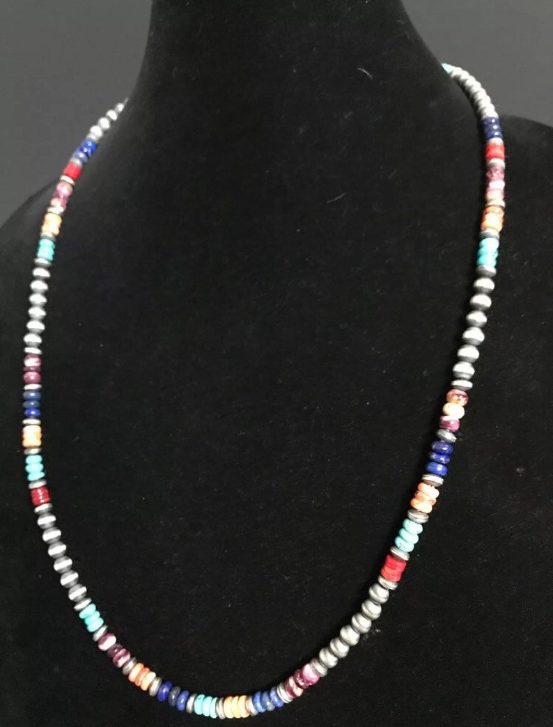 May include: A multi-colored beaded necklace with silver beads. The beads are in a repeating pattern of turquoise, orange, red, purple, blue, and silver.