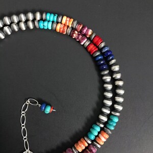 May include: A multi-strand necklace with silver beads and colorful stones. The stones are arranged in a rainbow pattern, starting with purple, then orange, turquoise, blue, and ending with lapis lazuli.