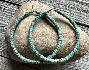 May include: A pair of turquoise hoop earrings made of small, square beads. The earrings are silver toned and have a hook closure.