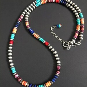 May include: A multi-colored beaded necklace with silver accents. The necklace features turquoise, coral, lapis lazuli, and other stones.