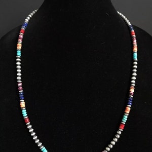 May include: A multi-colored beaded necklace with silver beads. The necklace features turquoise, lapis lazuli, coral, and other stones.