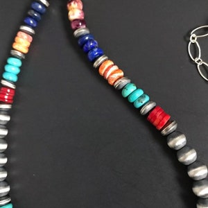 May include: A multi-colored beaded necklace with silver beads. The beads are in a rainbow pattern, with red, orange, yellow, green, blue, and purple beads.