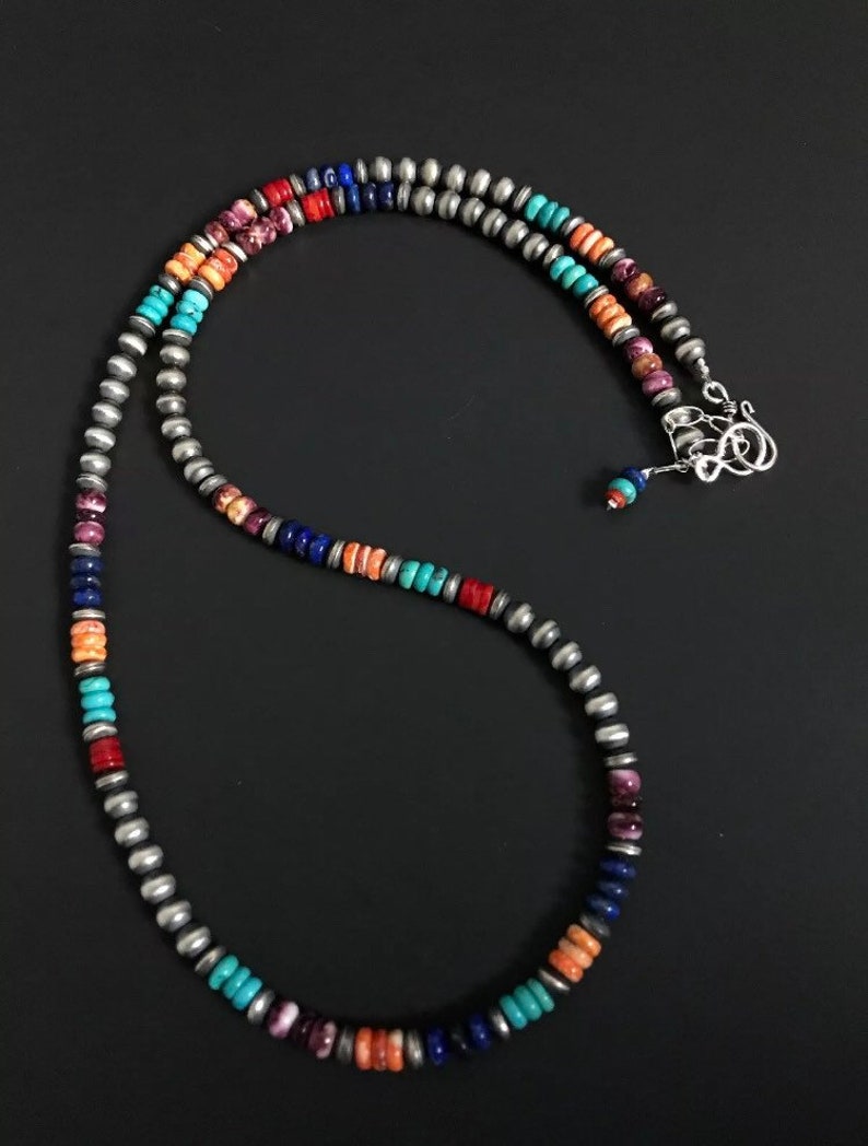 May include: A multi-colored beaded necklace with silver beads. The necklace features turquoise, coral, lapis lazuli, and purple stones.