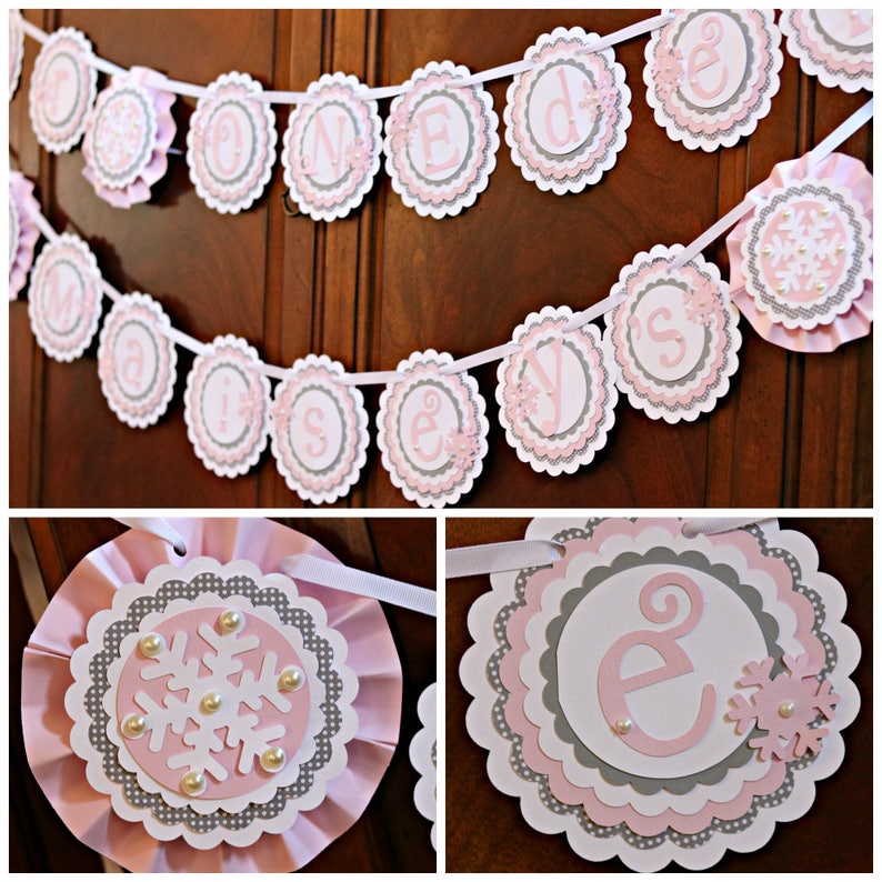 May include: A pink and gray banner with the text "Made with love" in a decorative font. The banner is made of layered paper circles with scalloped edges and snowflake accents. The banner is strung on a white ribbon.