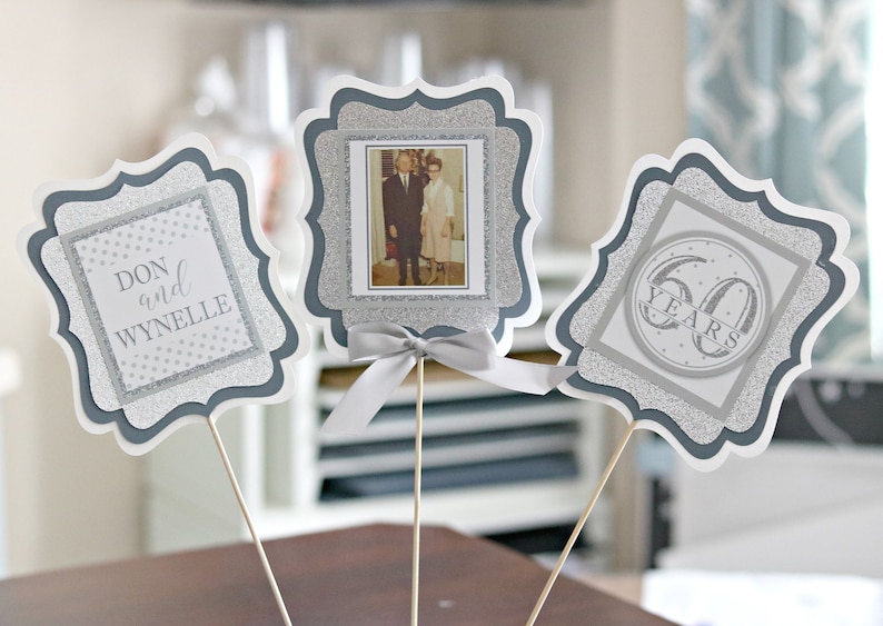 May include: Three silver glitter table centerpieces with a photo of a couple, the names Don and Wynnelle, and the text "60 Years".