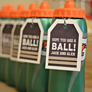 Puede incluir: Botellas de agua de pl&aacute;stico verde con tapas naranjas y etiquetas en blanco y negro que dicen "&iexcl;Espero que te lo hayas pasado genial! Jack y Alex".