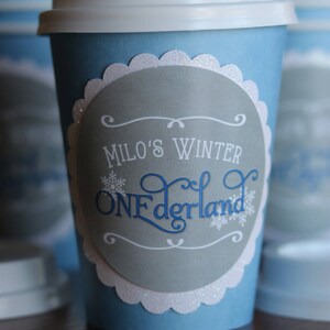 May include: Blue and white paper cup with a gray circle sticker that says "Milo's Winter Wonderland" in white and blue lettering.