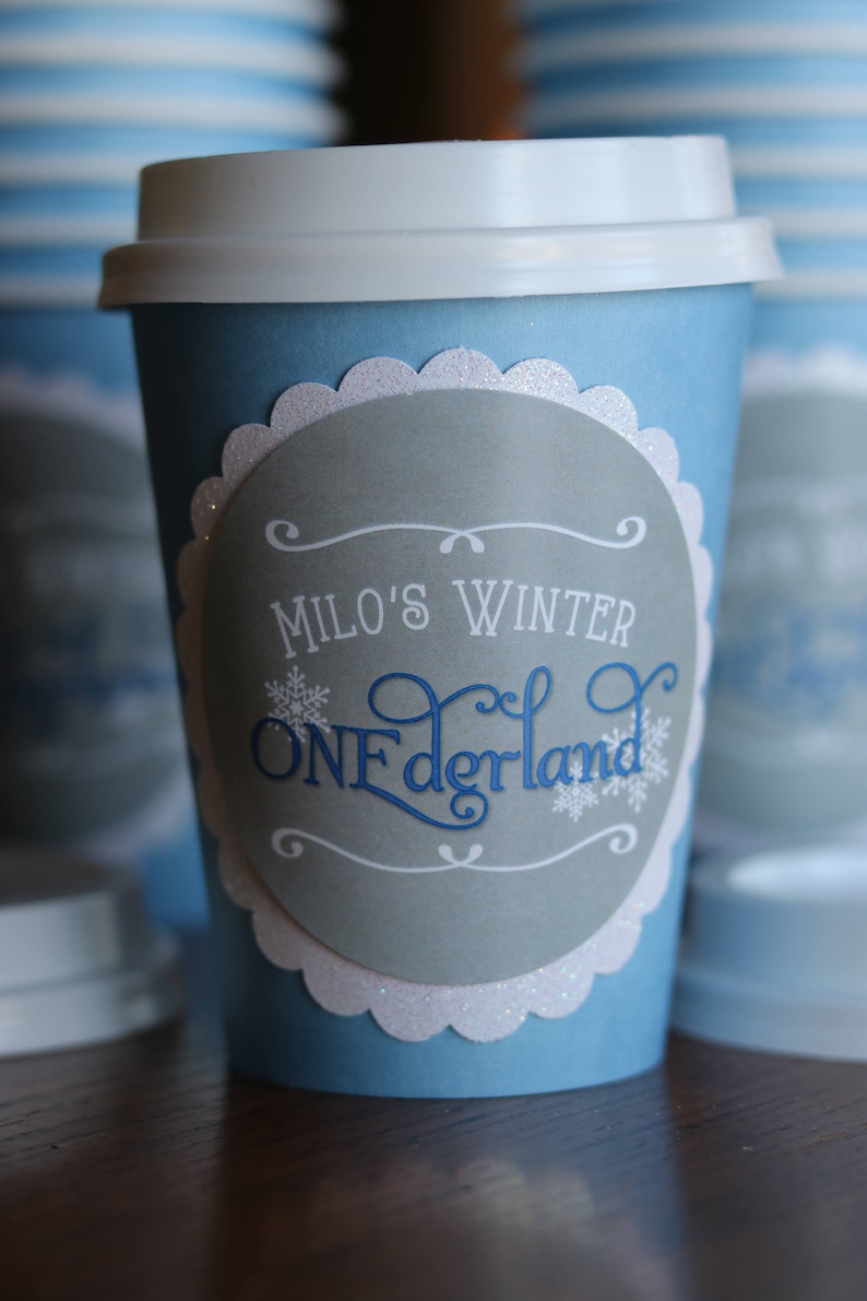 May include: Blue and white paper cup with a gray circle sticker that says "Milo's Winter Wonderland" in white and blue lettering.