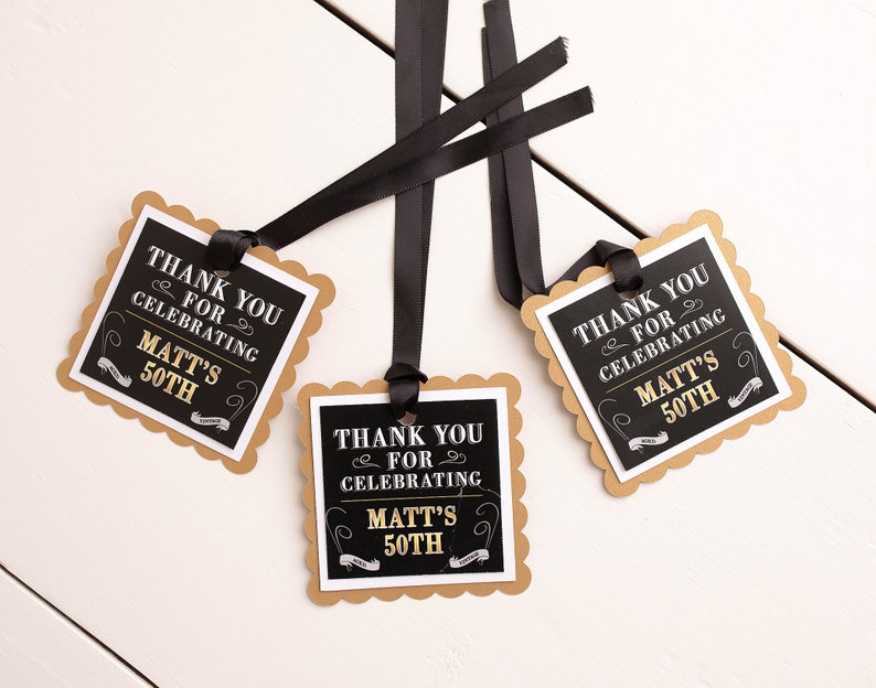 May include: Three black and gold favor tags with scalloped edges. The tags are tied with black ribbon and feature the text "Thank you for celebrating Matt's 50th".
