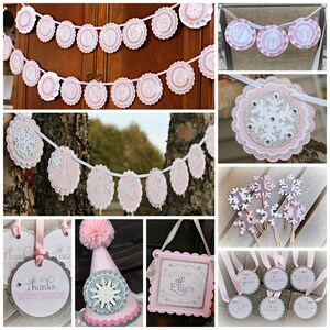 May include: A collection of pink, white, and silver party decorations featuring snowflake motifs. Items include scalloped banners spelling Ellie's One, monthly milestone markers, cupcake toppers, a party hat with a pom-pom, and signage.