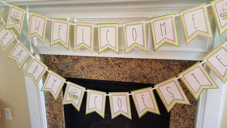 May include: A green and yellow banner with the words "Welcome Baby Coates" and a small book icon with the words "New Chapters" on it.